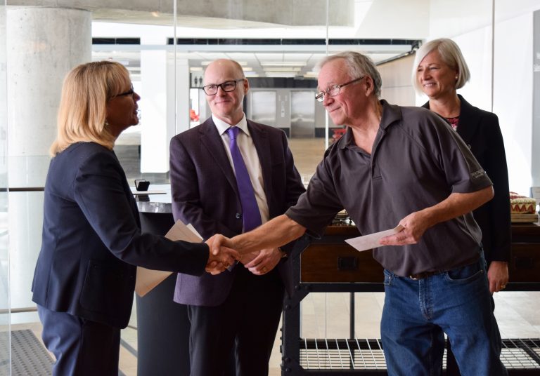 two people shaking hands and two people behind them