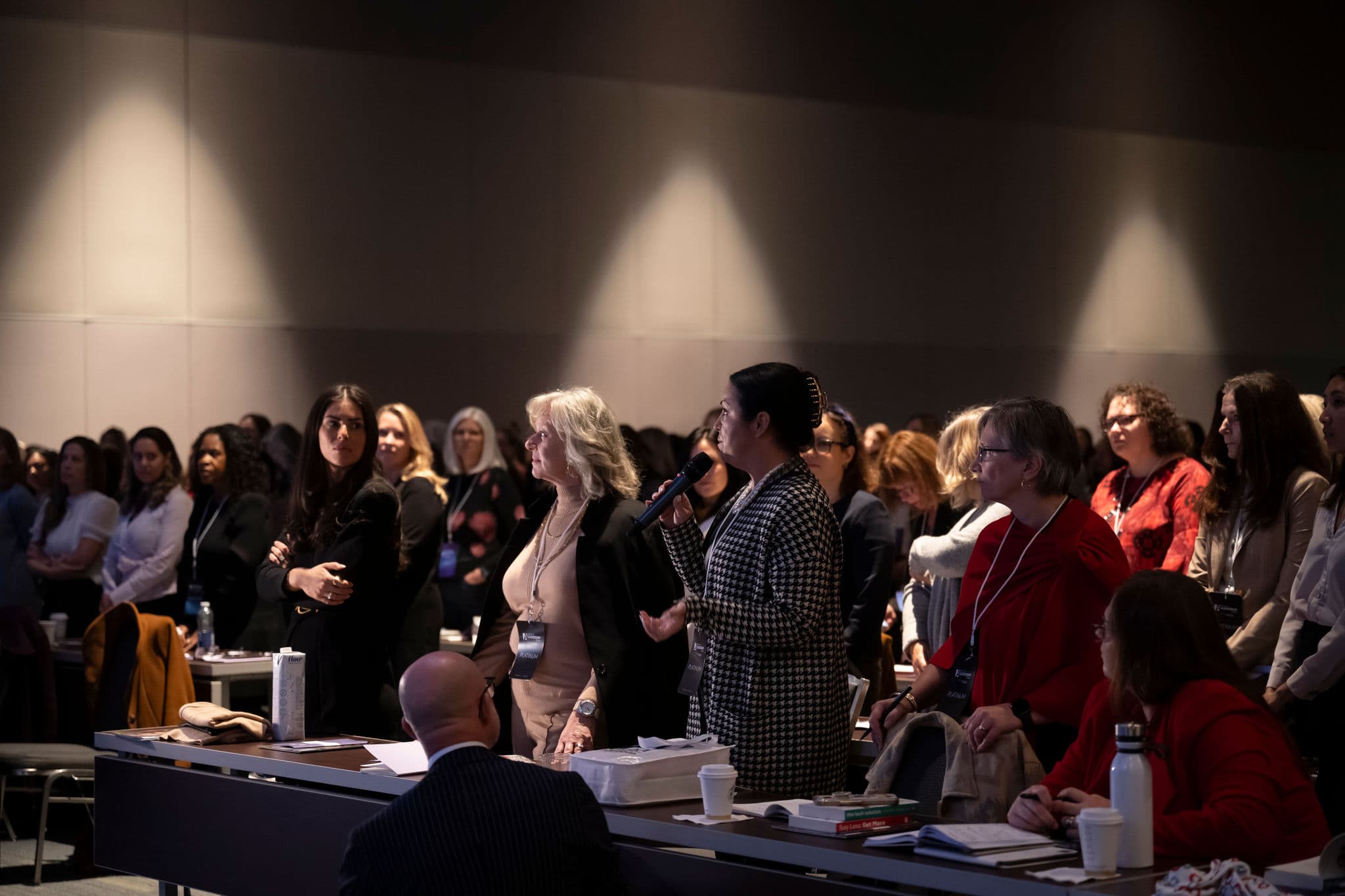 Attendees standing up with one women with the mic in her hand, the others are looking at her