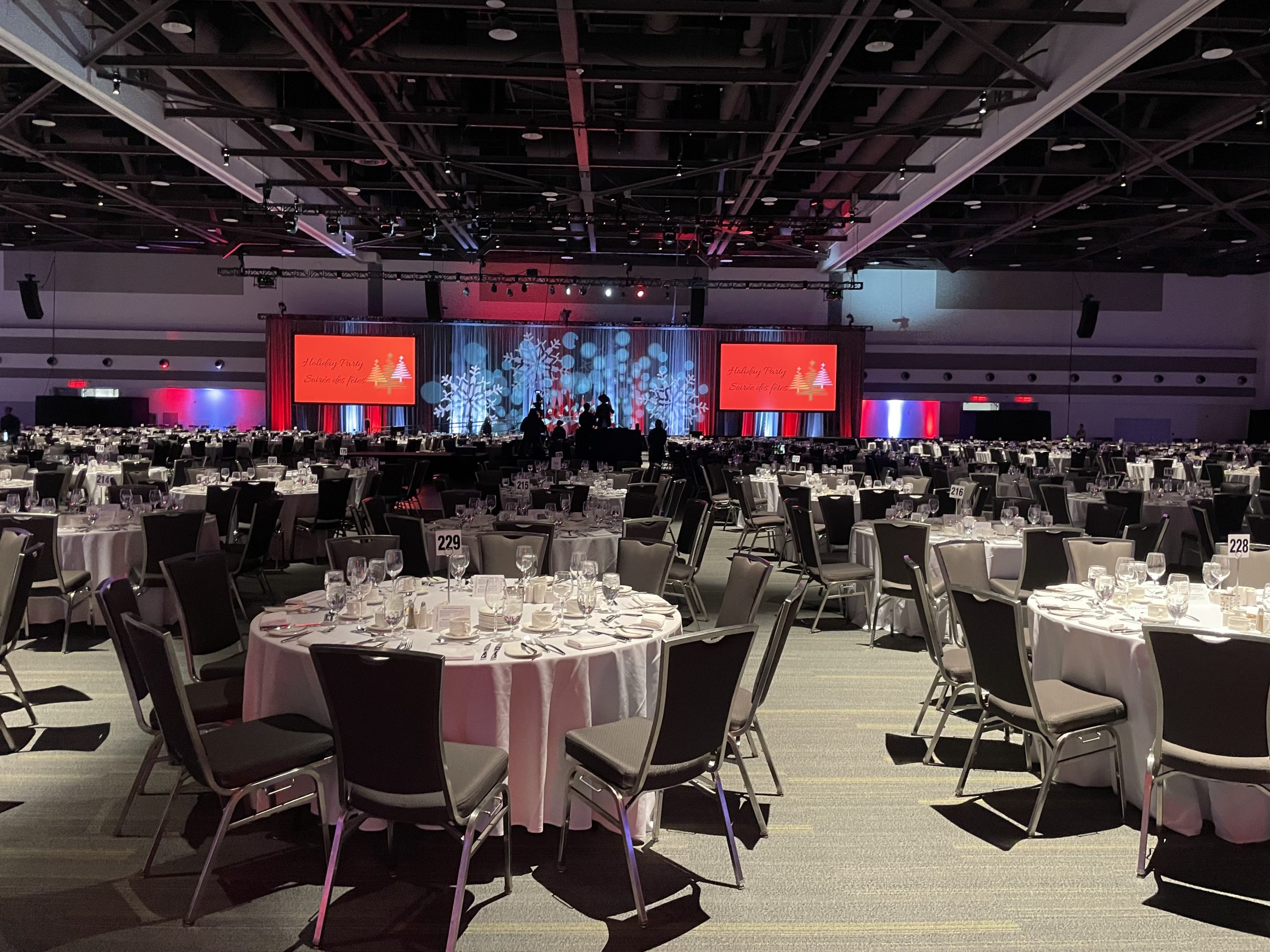 Holiday Party Set Up road tables with chairs around them with a stage