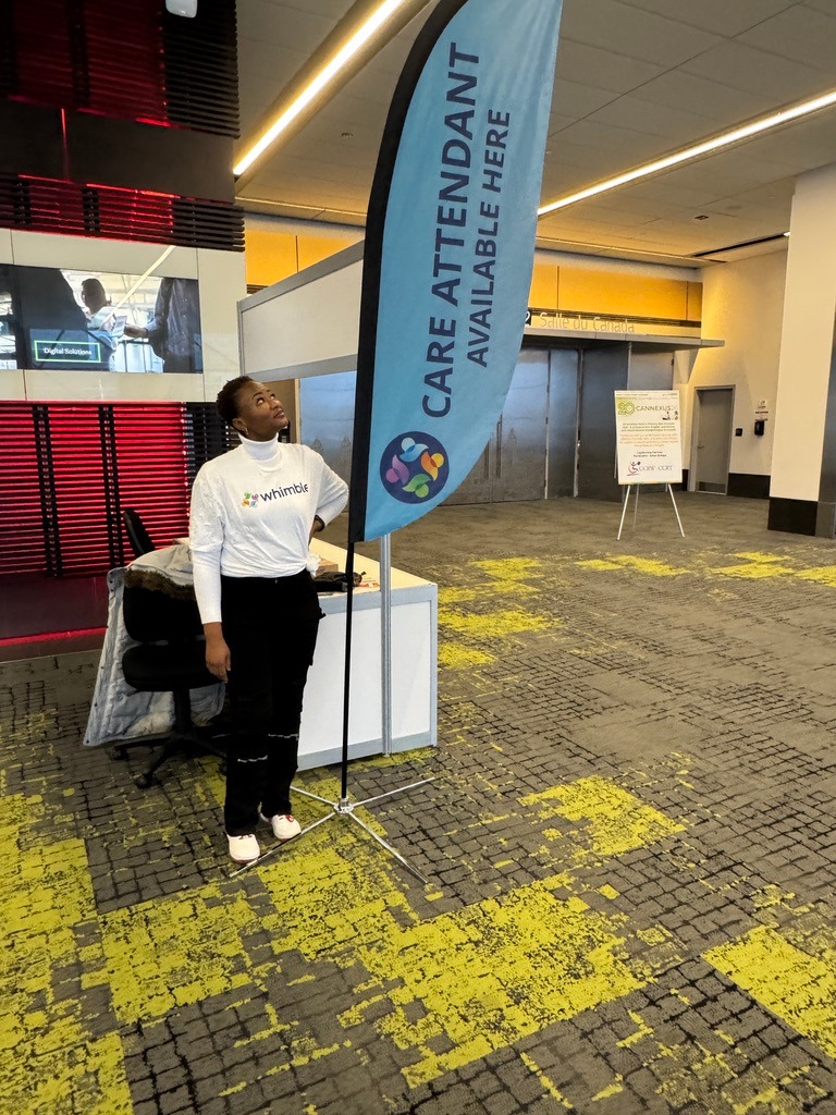 Whimble volunteer standing next to the Care Attendant Banner at the Whimble conference